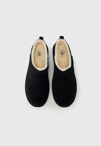 Μαύρα παπούτσια τύπου slip-on από καστόρι με απαλό, κρεμ χρώματος επένδυση από φλις. Διαθέτουν στρογγυλεμένη μύτη και ελάχιστες ραφές.