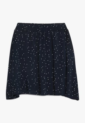 Jupe marine en tissu doux, avec une taille élastique froncée et un motif à pois blancs sur toute la surface. L'ourlet est légèrement asymétrique.