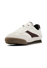 Sneaker bianco in suede con accenti marrone scuro, punta rotonda, design con lacci, suola in gomma texturizzata e striscia laterale distintiva.