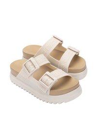 Sandales compensées beige avec deux sangles réglables, fabriquées en caoutchouc, arborant le nom de marque en relief et une semelle texturée pour une meilleure adhérence.