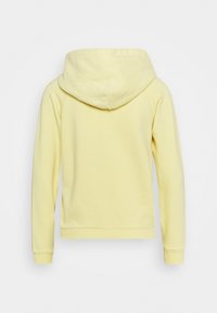 Gul huvtröja med en mjuk textur, som har en stor huva och ribbade cuffs. Enkel design, inga synliga logotyper eller mönster.