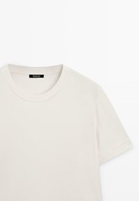 T-shirt blanc à manches courtes et col rond avec étiquette de col visible sur fond uni.