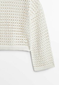 Valkoinen neulepaita, jossa on teksturoitu avoin malli, pyöreä pääntie ja ribatut hihansuut. Suunnittelu on kevyt ja hengittävä.