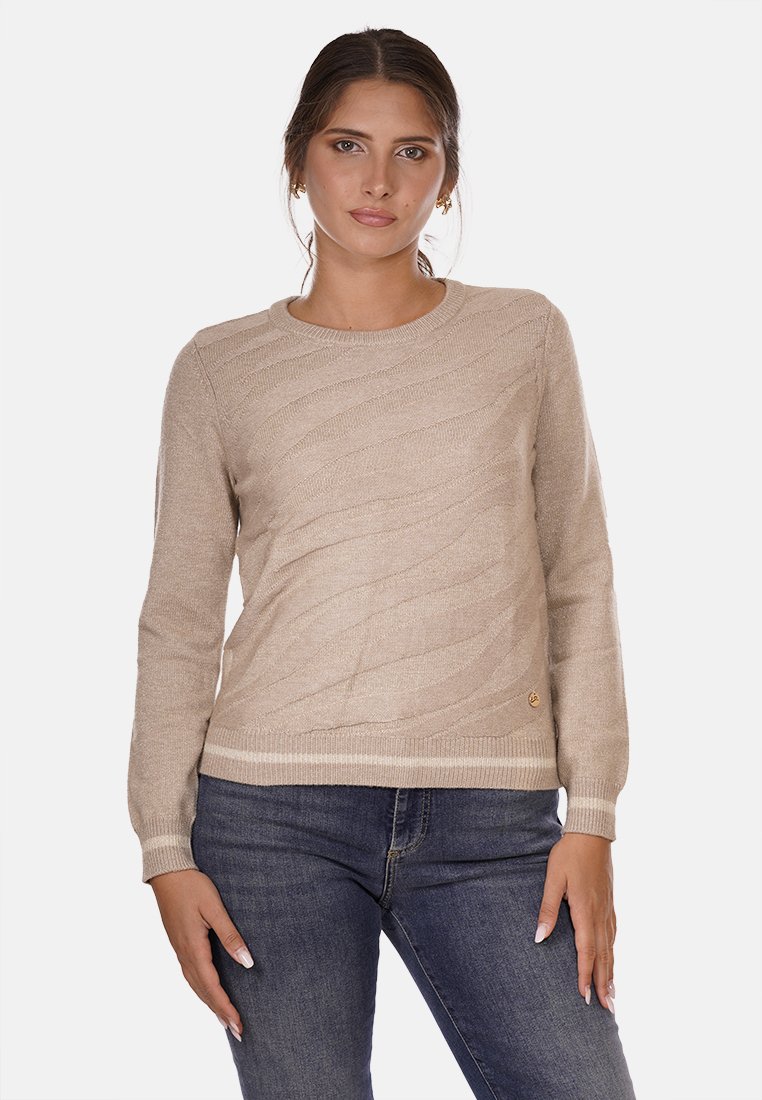 Jersey de punto beige con un patrón de olas texturizado, cuello redondo, mangas largas y puños acanalados, combinado con jeans de mezclilla oscura.