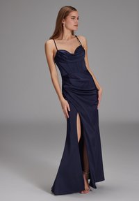 Robe en satin marine avec un décolleté drapé, un corsage plissé, une fente sur le côté et une silhouette ajustée, soulignée par de fines bretelles.