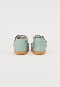 Myntgrønne sandaler med en glat læderfinish, justerbare remme og en tan gummisål. Indeholder udskæringsdetaljer for åndbarhed.