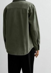 Groen, oversized shirt met een kraag, lange mouwen en een gebogen zoom. Gemaakt van een lichtgewicht stof met een gladde textuur.
