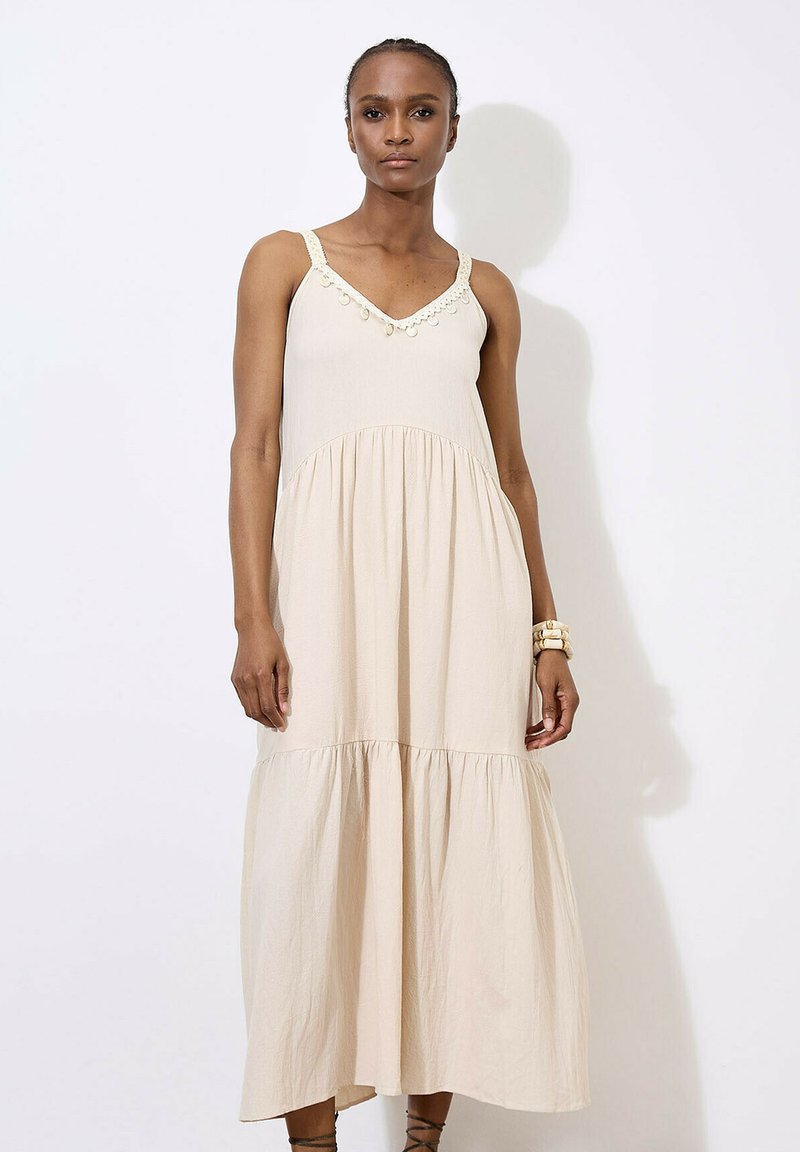 Beige bezramínkov dress s výstřihem do V, dekorativním šitím a sukni s volány. Vyrobeno z lehkého materiálu, s volně splývajícím designem.