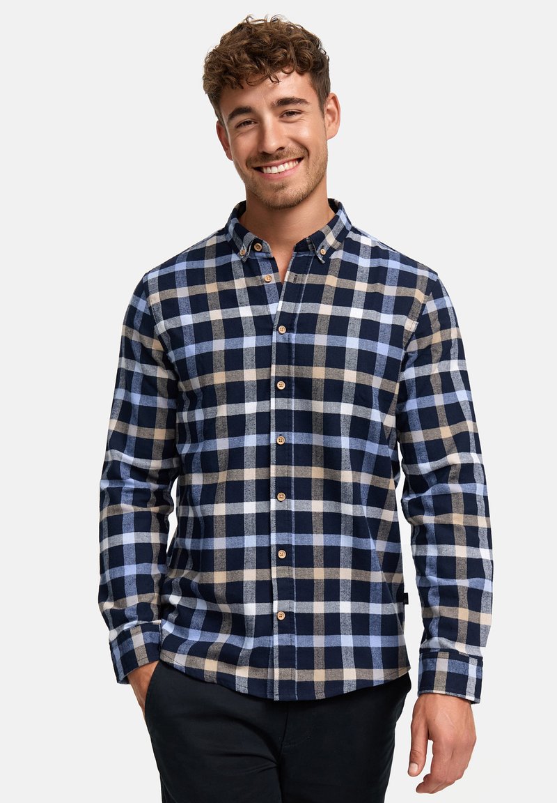 Camisa de franela a cuadros en azul marino, azul claro y marrón. Presenta un cuello de botón y botones en la parte delantera, con mangas largas y un corte holgado.