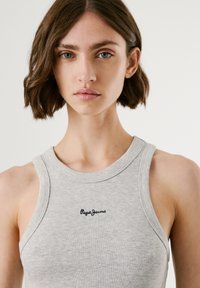 Graues geripptes Tanktop mit rundem Ausschnitt, ausgestattet mit einem schwarzen "Pepe Jeans" Logo, das auf der Vorderseite gestickt ist. Glatte Textur.