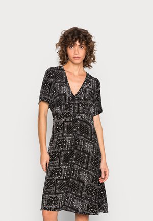 Vestido preto com padrão, de mangas curtas, decote em V e forma A. Apresenta padrões geométricos brancos e pontos por todo o vestido.