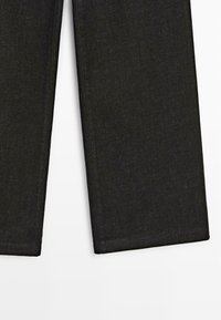 Sorte denim bukser med lige ben-design, der har en subtil struktur og minimal kontrastsyning langs sømmene.