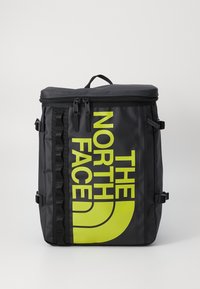 Sac à dos noir fabriqué avec un matériau durable, arborant un logo jaune audacieux. Comprend une fermeture à glissière, des sangles latérales et un design structuré.