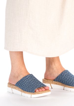 Sandales en textile bleu avec un motif tissé, semelle en liège rembourrée et semelle extérieure blanche. Assorties à un vêtement de couleur claire.