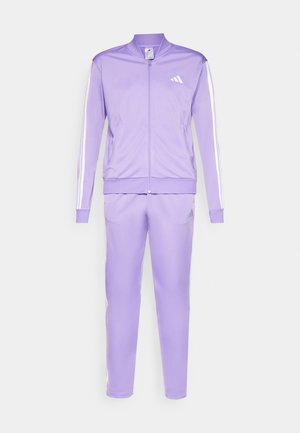 Completo sportivo viola realizzato in materiale sintetico liscio. Giacca con colletto alto, chiusura a zip frontale e strisce bianche sui lati. I pantaloni presentano una vestibilità slim.