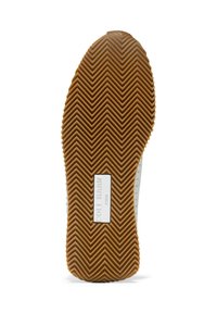 Brun gummisula med ett fiskbensmönster. Har en vit logotext i centrum som anger märke och etableringsår.