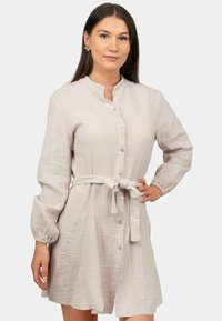 Vestito button-up beige chiaro realizzato in tessuto testurizzato, dotato di colletto alla mandarino, maniche lunghe e vita con cintura.