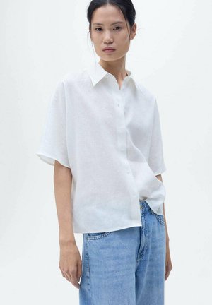 White linen short-sleeve shirt with a button-up front and a classic collar, paired with light blue denim jeans. Simple and relaxed design.