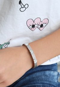 Zilveren mesh armband met hartvormige accenten, met kleine sprankelende details. Draag op een pols met een casual shirt en denim.