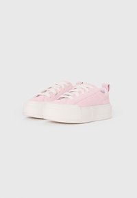 Baskets en daim rose avec des lacets blancs et une épaisse semelle compensée blanche. Présentent une tirette au talon pour un enfilage facile. Texture lisse.