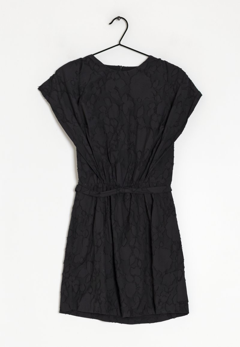Robe noire en matériau texturé, avec des manches courtes, une taille élastique et une coupe ample, suspendue à un crochet noir.