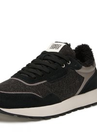 Sneaker nero e grigio con una parte superiore in feltro testurizzato, dettagli in suede e suola ammortizzata. Presenta lacci a contrasto e un'etichetta con logo.