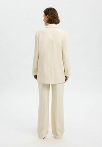 Off-white skræddersyet blazer og vide bukser med en struktureret design, glat tekstur og knapdetaljer på ærmerne.