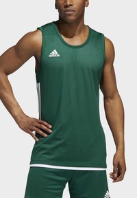 Grünes ärmelloses Sporttanktop aus atmungsaktivem Material, mit weißen Seitengürteln und einem Adidas-Logo auf der Brust.