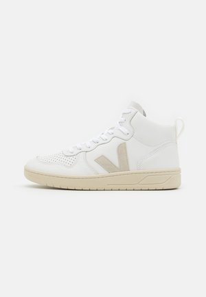Hochformatige Sneakers aus weißem Leder mit beigen Wildlederelementen, perforierter Zehenpartie, weißen Schnürsenkeln und einer strukturierten cremefarbenen Gummisohle.