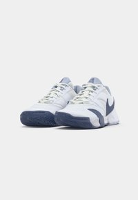 Et par hvite og marineblå Nike-sneakers med snørebånd, plassert side om side på en hvit bakgrunn.