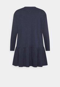 Granatowa sukienka z długim rękawem, wykonana z miękkiego materiału, z falbaną u dołu i prostym dekoltem zaokrąglonym. Widok z tyłu.