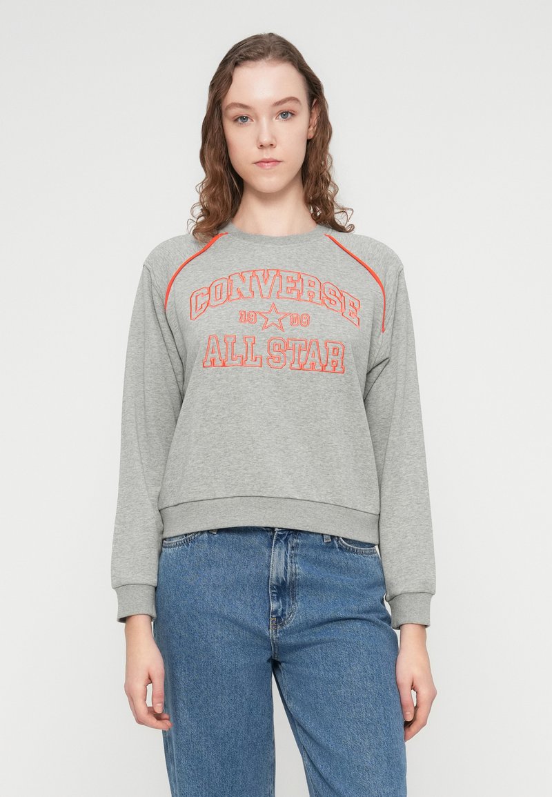 Grå sweatshirt med rød "Converse All Star"-tryk. Har lange ærmer, rund halsudskæring og ribkant i bunden. Casual pasform og blød tekstur.