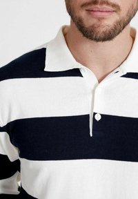 Polo a righe blu navy e bianche realizzato in cotone lavorato a maglia, con colletto, tre bottoni e un tessuto testurizzato.