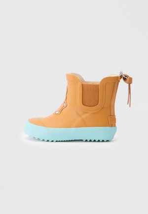 Oranžās gumijas potītes zābaki ar strukturētu, gaiši zilu ārējo zoli. Ir brūna auduma ievietojums un dekoratīvā šūšana priekšpusē.