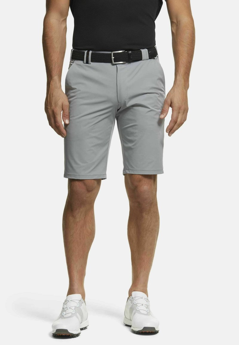 Un short de golf gris avec une texture lisse, des passants de ceinture et une poche avant. Associé à des baskets blanches et un t-shirt noir ajusté.