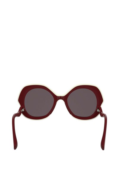 Occhiali da sole bordeaux con forma cat-eye scultorea, dotati di lenti scure e una montatura in crema a contrasto. Texture in plastica liscia.