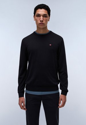 Schwarzer Pullover mit Rundhalsausschnitt, langen Ärmeln und gerippten Bündchen. Verfügt über ein kleines rot-weißes Logo auf der Brust. Getragen über einem blauen Hemd.
