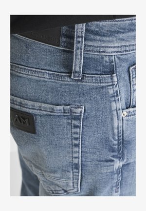 Close-up of blue denim jeans back with visible belt loop, pocket stitching, and two black brand labels reading Antony Morato and AM1.