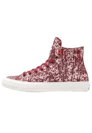 Wysokie sneakersy z czerwono-białym pikselowym wzorem, czerwonymi sznurówkami, metalowymi przelotkami i białą gumową podeszwą.