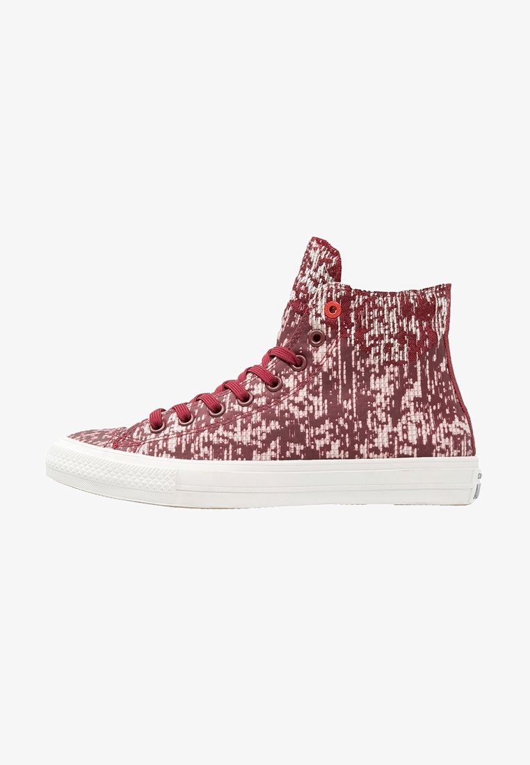 Baskets montantes avec motif pixellisé rouge et blanc, lacets rouges, œillets métalliques et semelle en caoutchouc blanche.