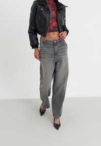 Chaqueta de cuero negra ajustada, top corto floral burdeos, jeans baggy gris de cintura alta y tacones negros de punta. Tejidos suaves y texturizados.