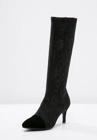 Stivali neri al ginocchio con sovrapposizione in pizzo, punta affusolata e punta in suede nera. Il tacco ha un design sottile a stiletto.