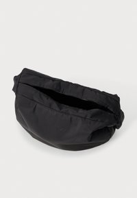 Bolso de hombro negro de nylon con un diseño suave y plegable. Presenta un cierre superior con cremallera y un sutil logo en relieve en la parte frontal.