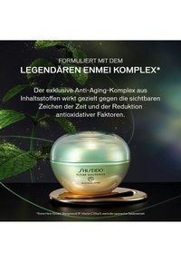 Shiseido Future Solution LX crèmedoos op een gouden dienblad met groene bladeren en Duitse tekst over anti-verouderingsenzymcomplex ingrediënten.