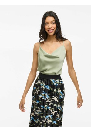 Camisole en satin de couleur vert clair avec des fines bretelles, associée à une jupe plissée noire ornée d'un motif abstrait multicolore en bleu et vert.