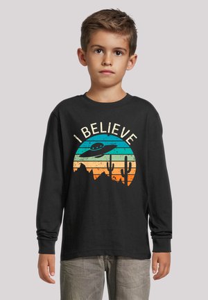 Schwarzes Langarm-T-Shirt mit einem bunten Sonnenuntergangs-Graphic, dem Satz "ICH GLAUBE", Kakteen und einer UFO-Silhouette.