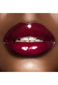Glossy, deep burgundy lips with prominent shine, showcasing smooth texture and subtle highlights against a warm skin tone background.
