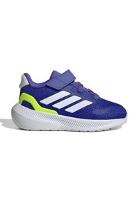 Zapatilla deportiva morada con parte superior de malla, rayas blancas y acentos verde lima. Presenta una correa de velcro y suela blanca texturizada.