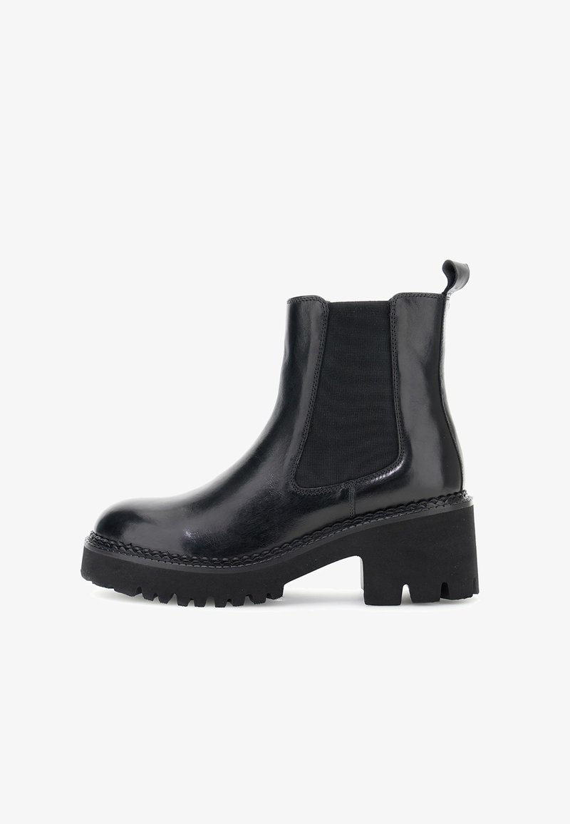 Mustat nahkaiset Chelsea-saappaat, joissa on paksu urasohva, elastinen sivupaneeli, vetotappi ja paksu korko valkoista taustaa vasten.