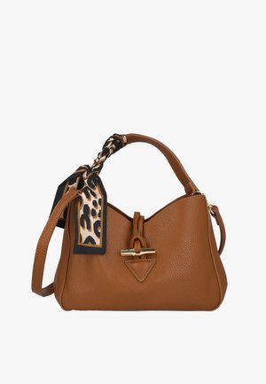 Bolso de cuero color tan con forma triangular, que presenta un asa trenzada, herrajes dorados y un pañuelo decorativo con estampado de leopardo.